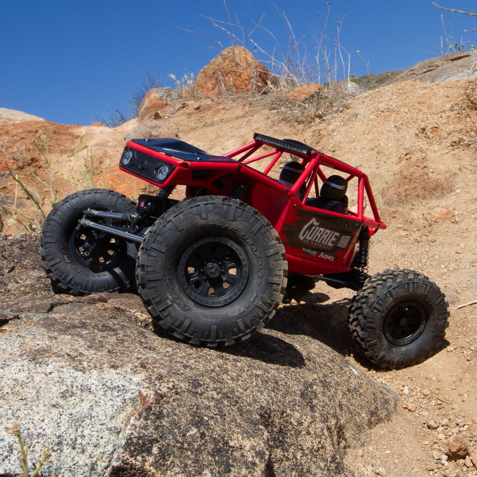 A rc truck is sitting on top of a rock wall next to a waterfall.