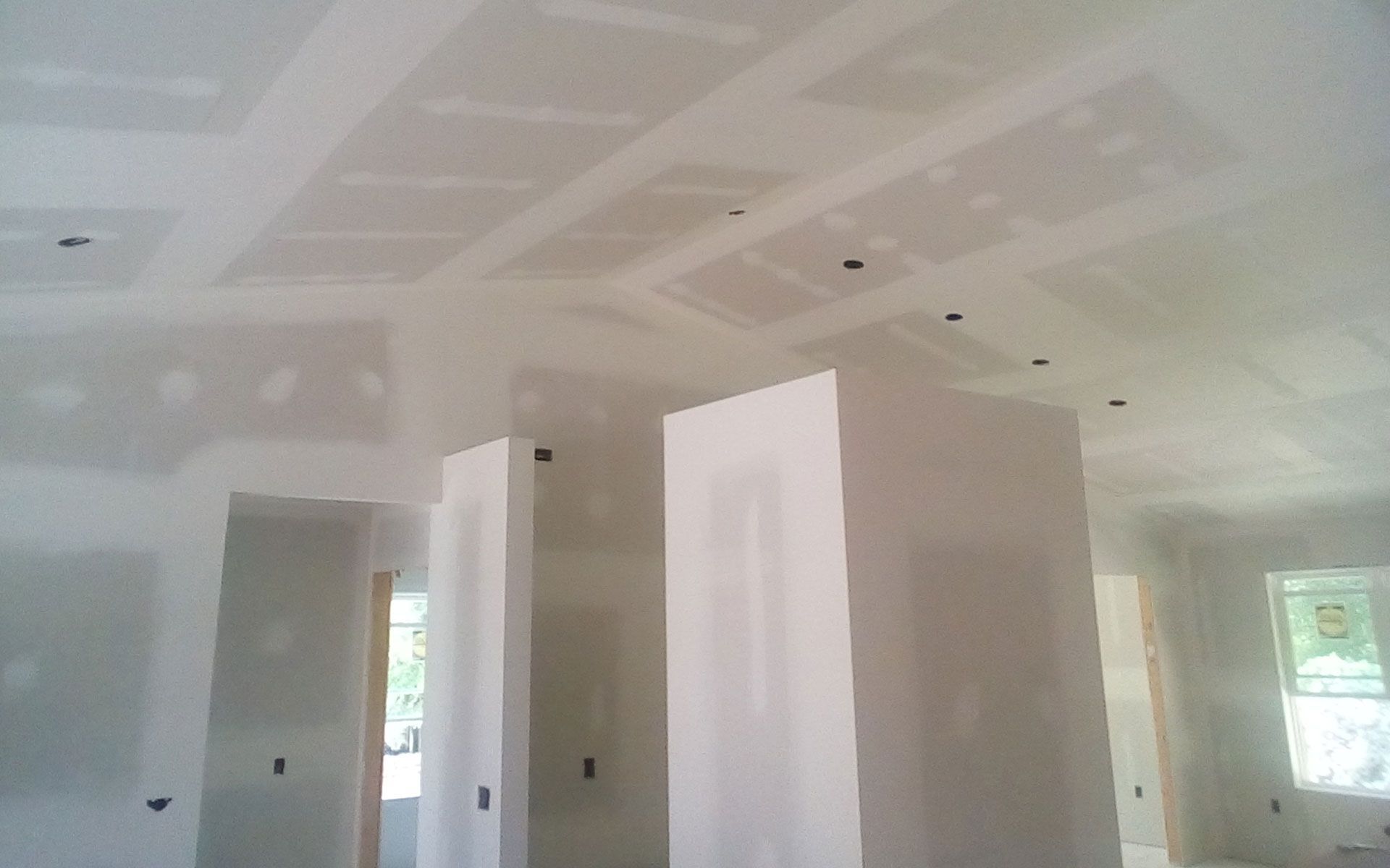 Interior view of a room under construction with drywall walls and ceiling, including recessed panels.