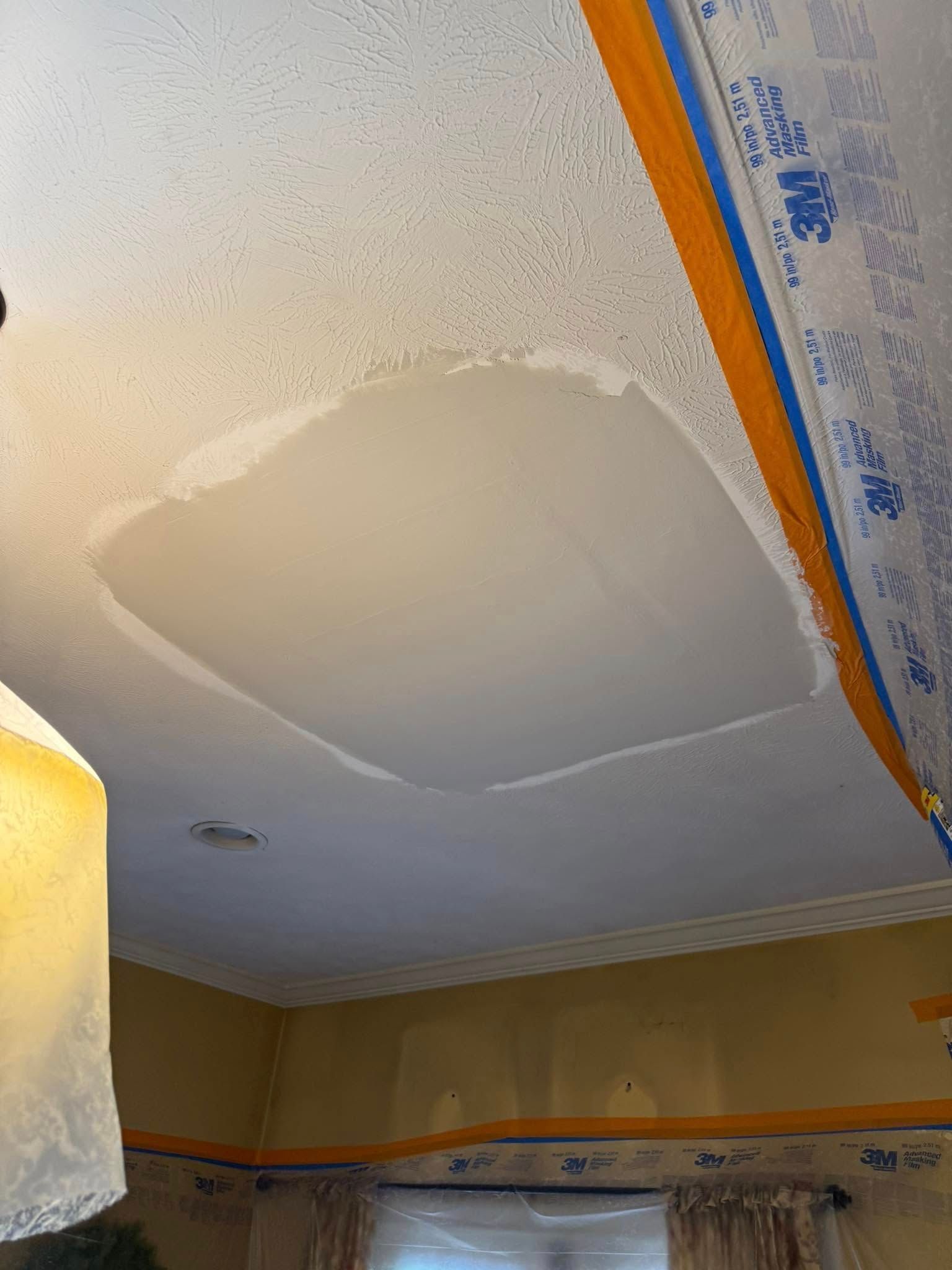 Person scraping textured ceiling with a long-handled tool, removing debris, indoors.