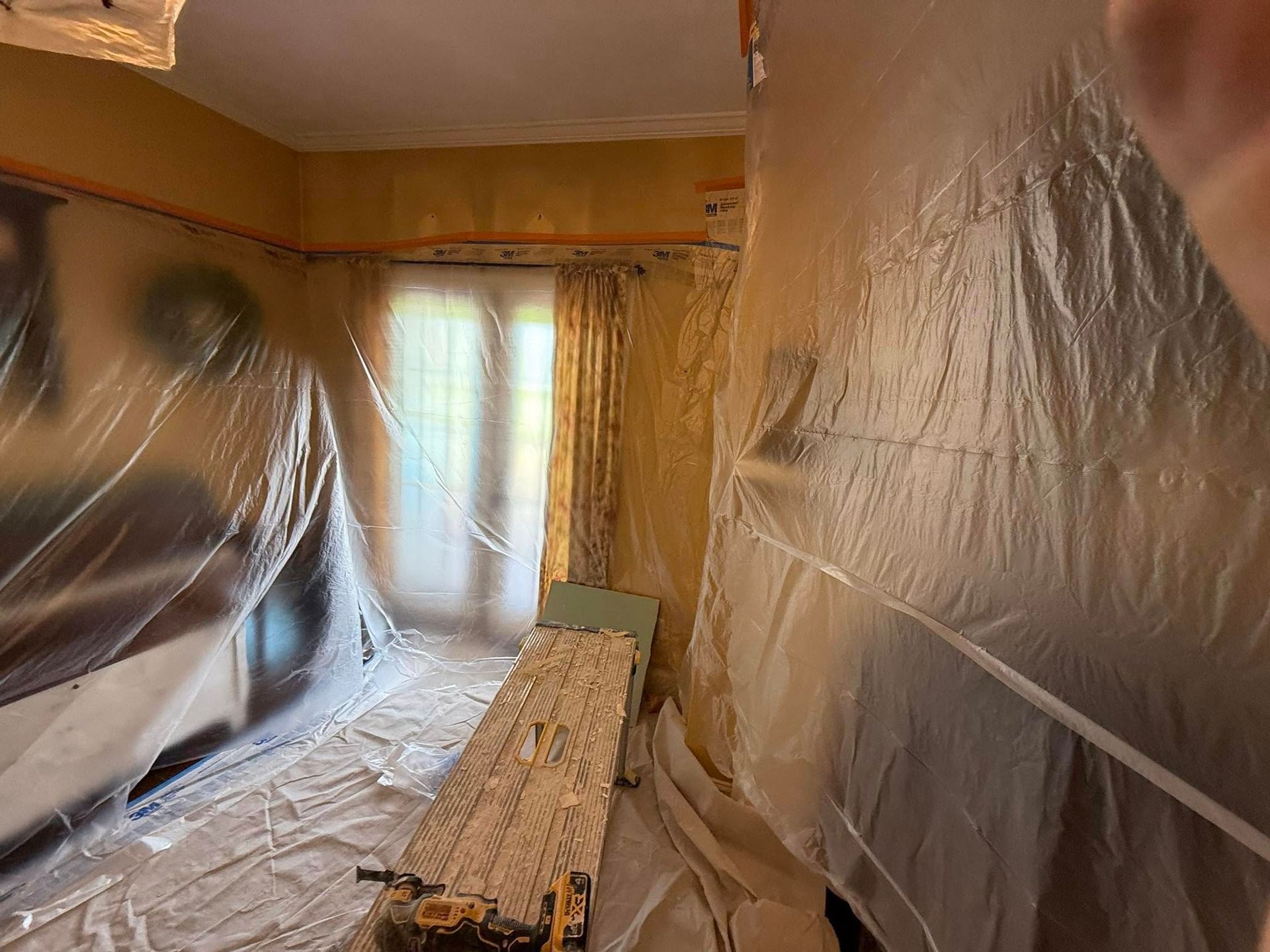 Person with gloved hand using a trowel to apply compound to a wall; close-up shot.
