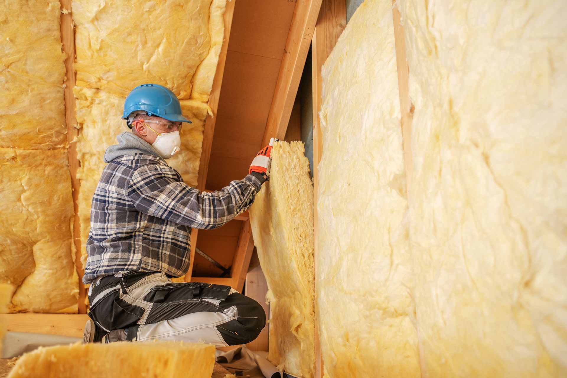 Person in protective suit spraying insulation into ceiling.