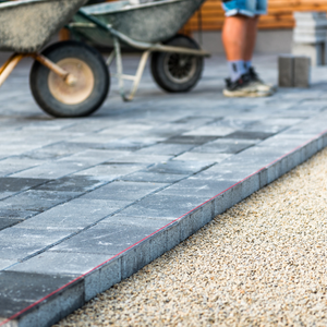 A driveway in Hastings being constructed with grey blocks. The lower half the legs of a contractor can be seen in the background.