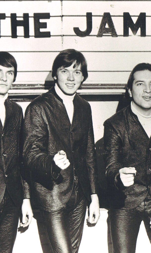 The Jam, a British band, posing outdoors. Three men in suits.
