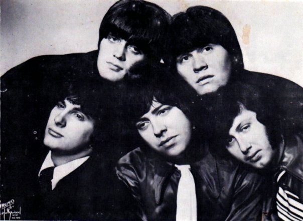 Black and white photo of a 5-man band. They all have shaggy hair and are looking at the camera.