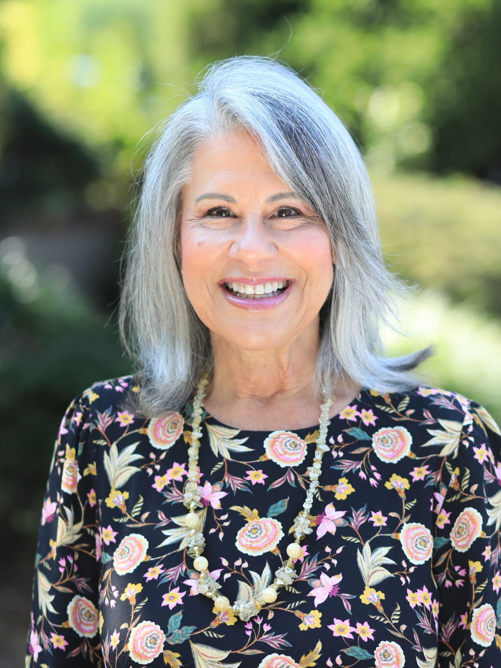 Natural light headshots with a blurred green background.