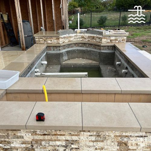 A swimming pool under construction with a tape measure on the edge