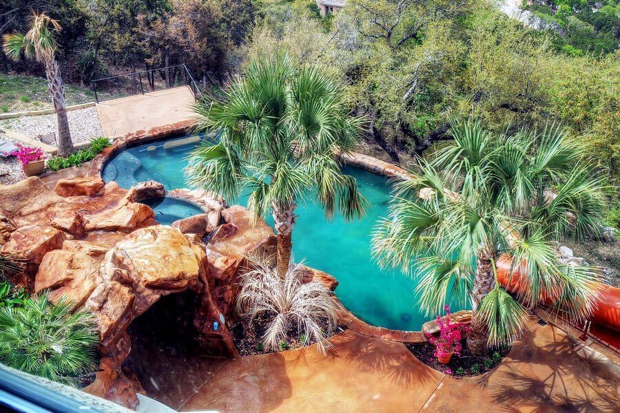 An aerial view of a large swimming pool surrounded by palm trees.