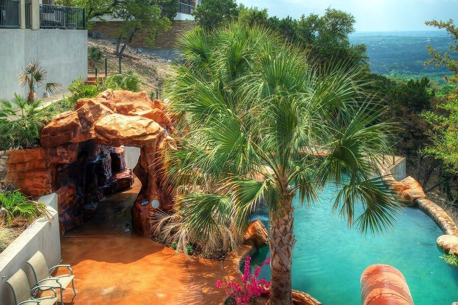 A large swimming pool surrounded by palm trees and rocks
