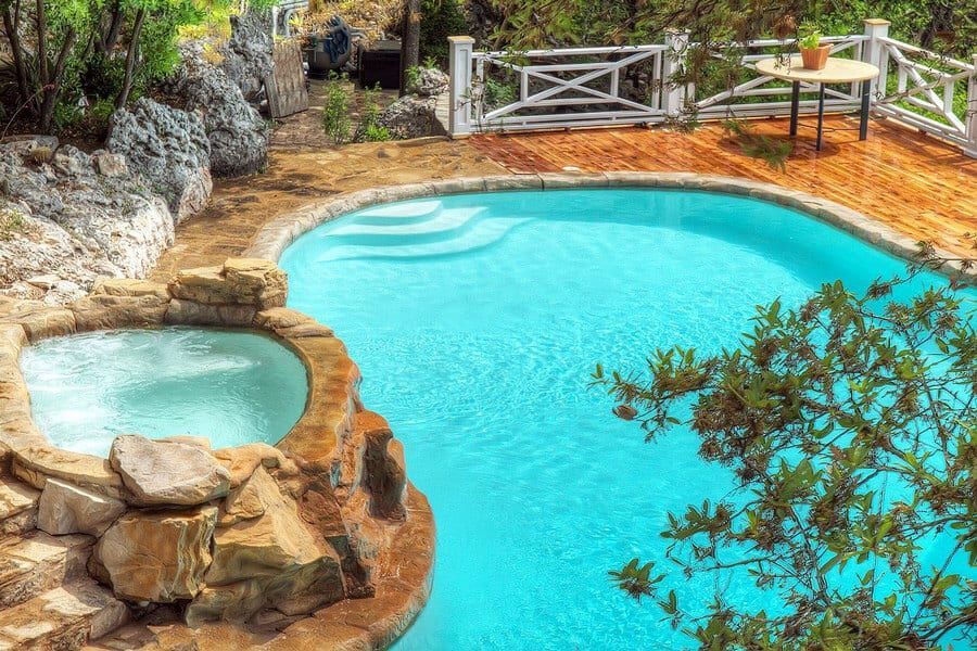 A large swimming pool with a hot tub in the middle of it.