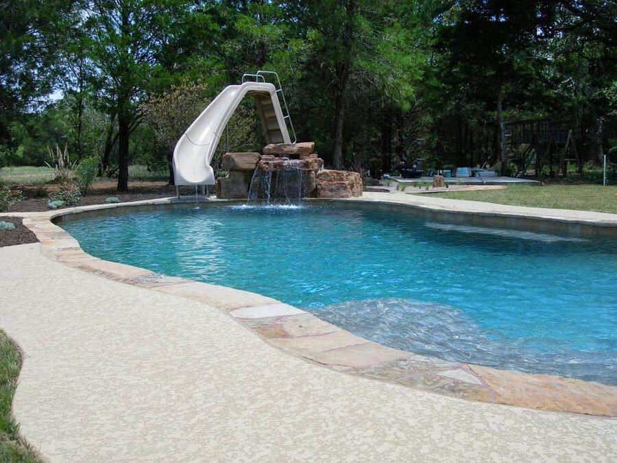 A large swimming pool with a water slide and a waterfall