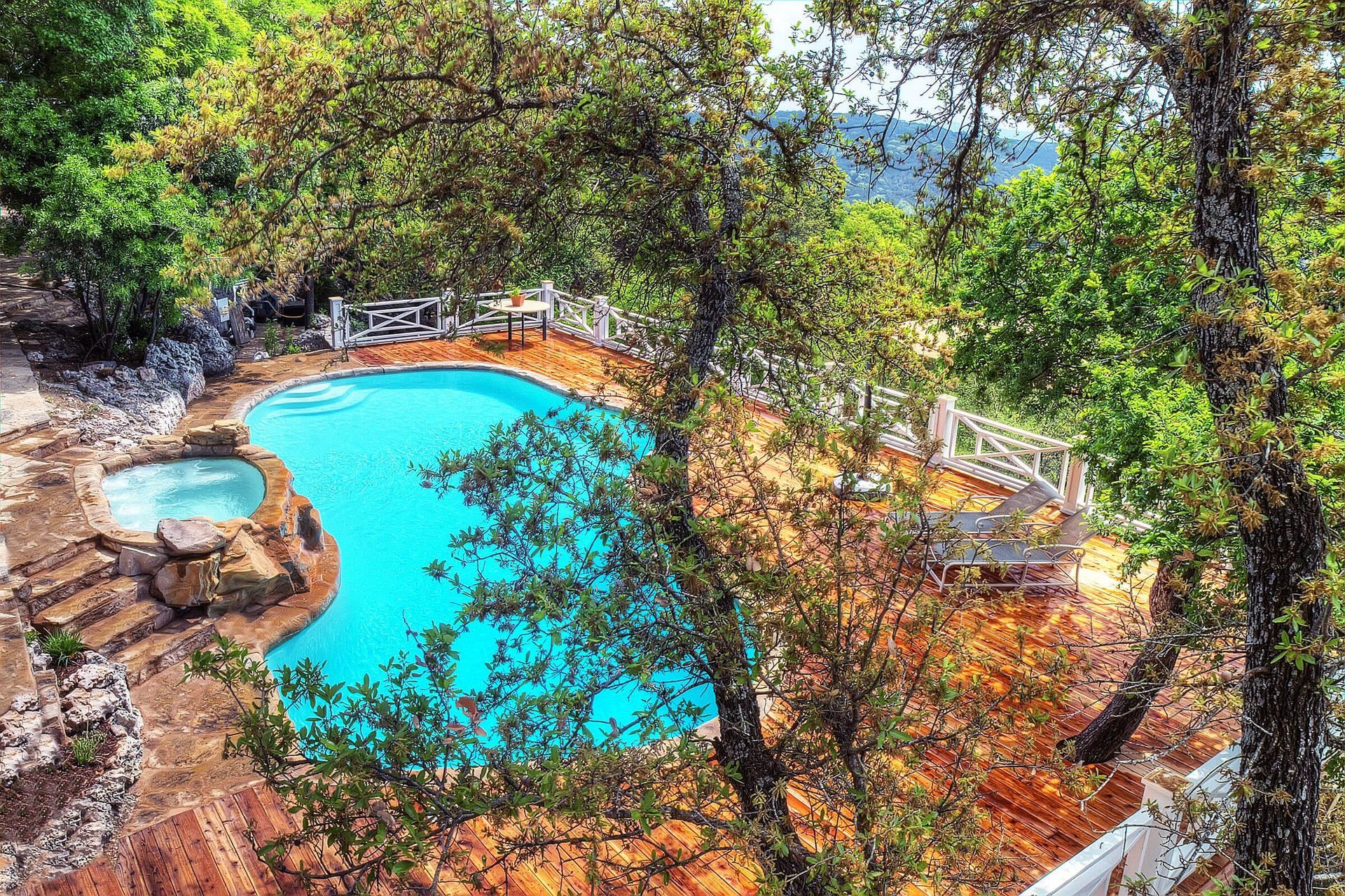 An aerial view of a large swimming pool surrounded by trees.