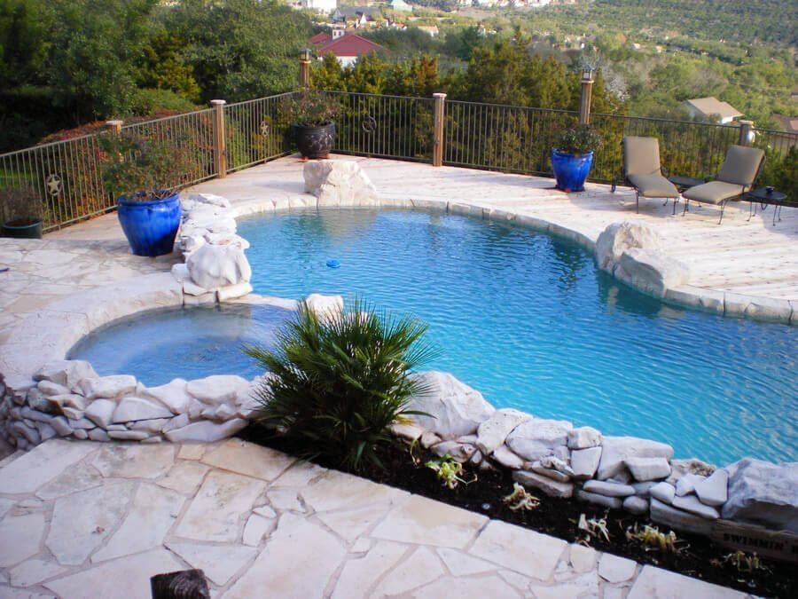 A large swimming pool surrounded by rocks and chairs