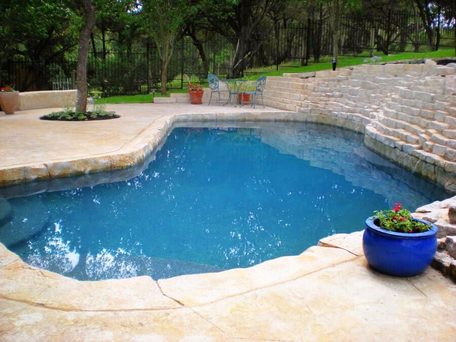 A large swimming pool with a blue pot of flowers on the edge.