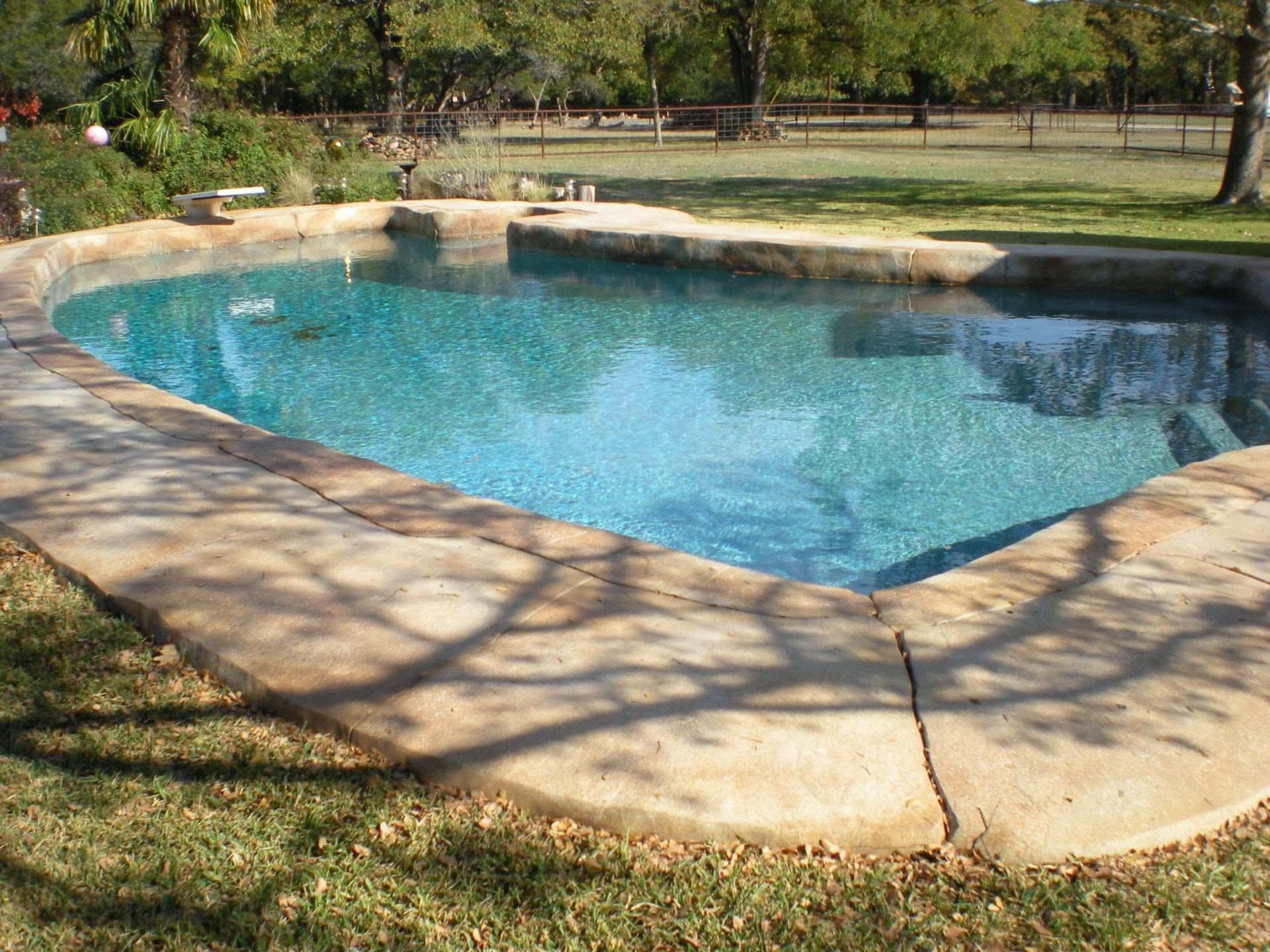 A large swimming pool surrounded by grass and trees