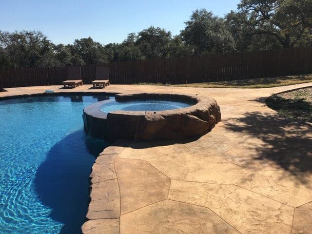 A large swimming pool with a hot tub in the middle