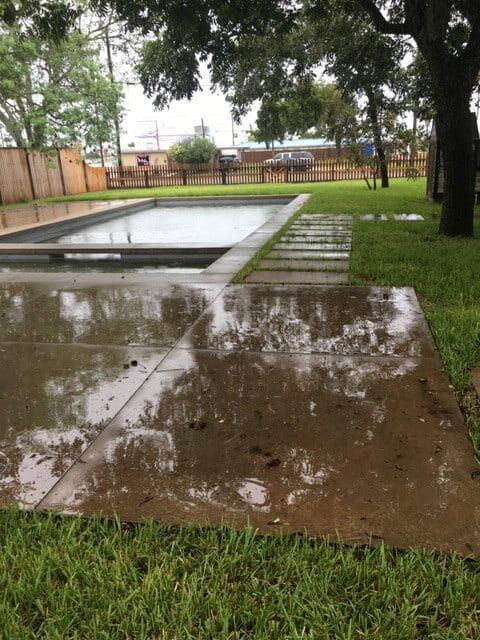 A swimming pool is surrounded by a lush green lawn