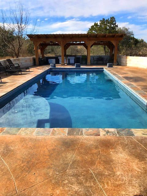 A large swimming pool with a gazebo in the background