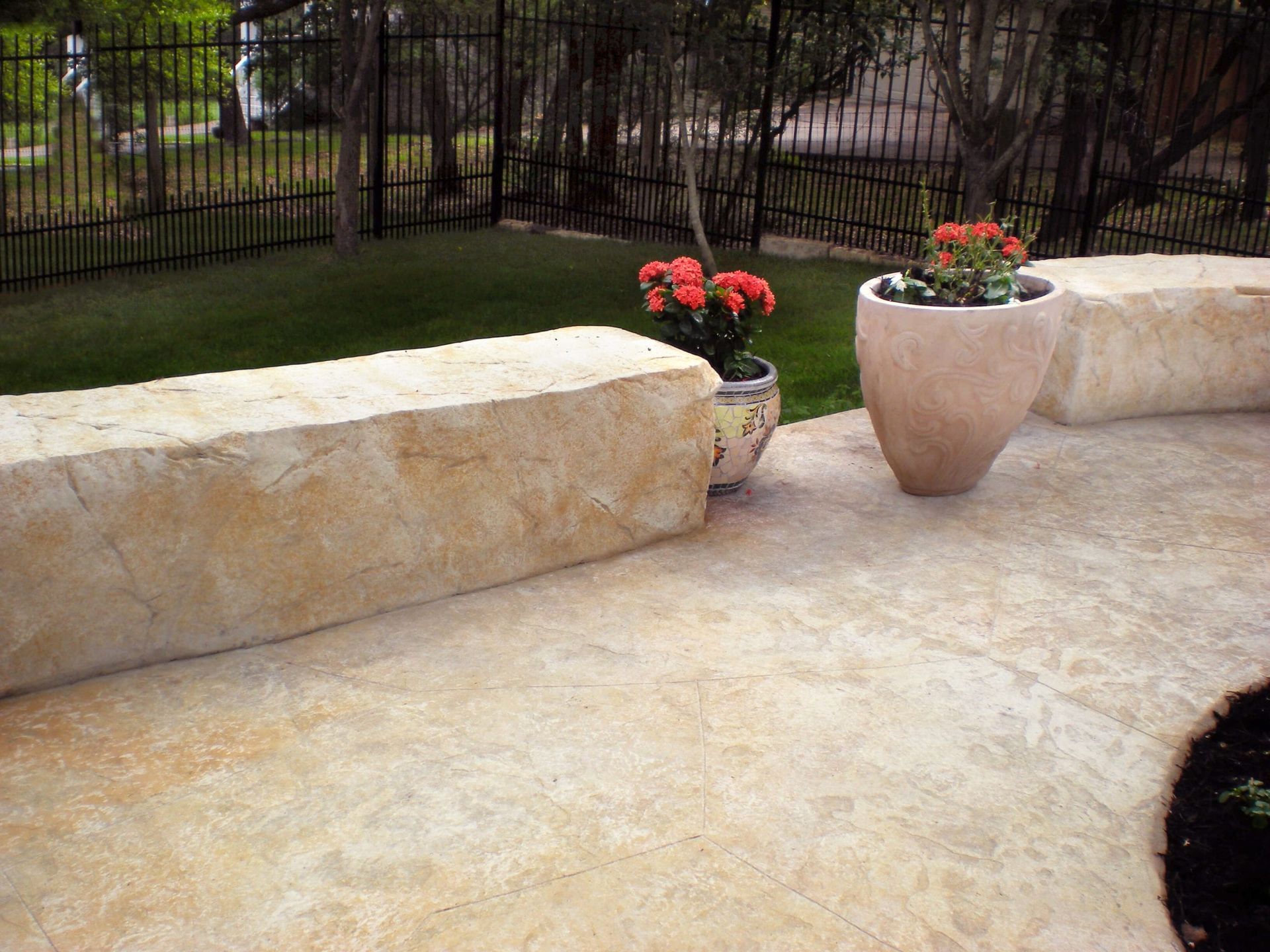 A patio with potted plants and a fence in the background
