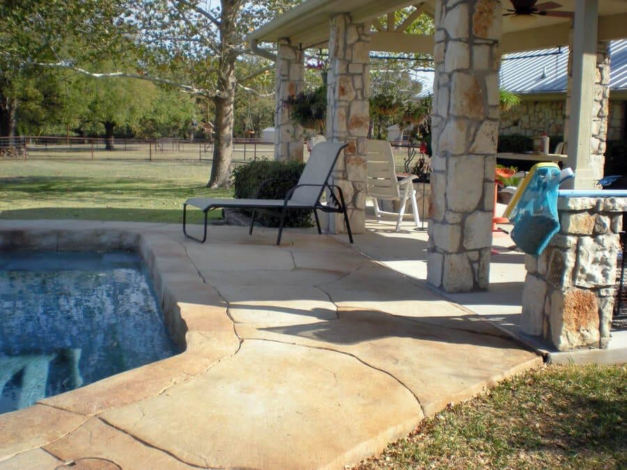 A patio with a swimming pool in the background