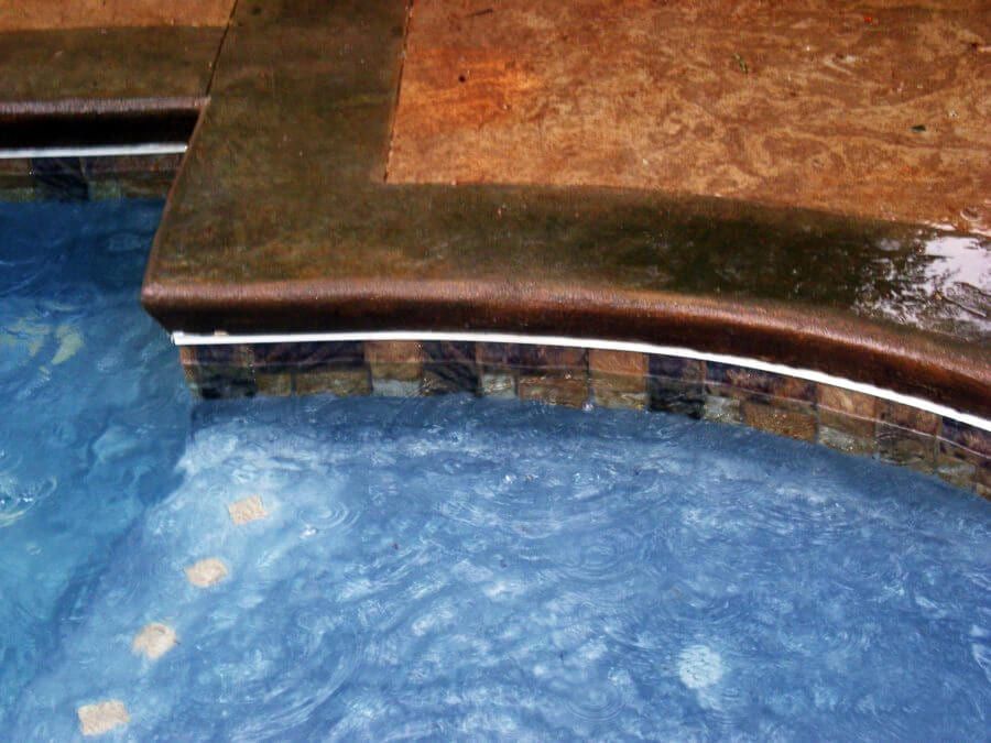 A close up of a swimming pool with blue water and a tiled edge.