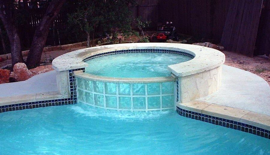 A swimming pool with a hot tub in the middle of it