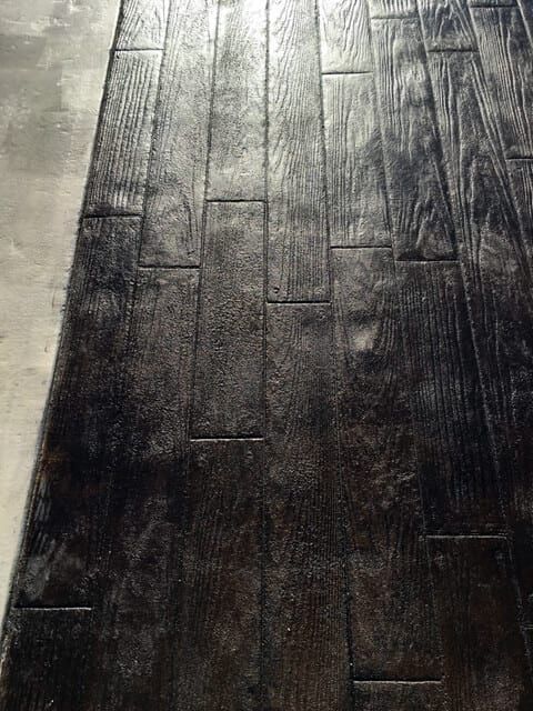 A close up of a black concrete floor that looks like wood.
