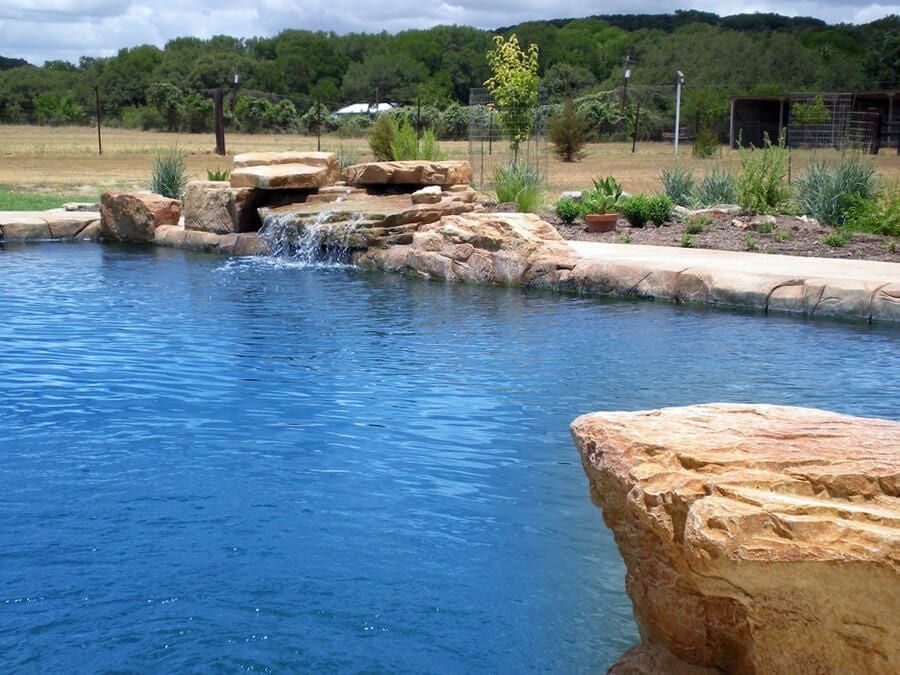 A large swimming pool with a waterfall in the middle