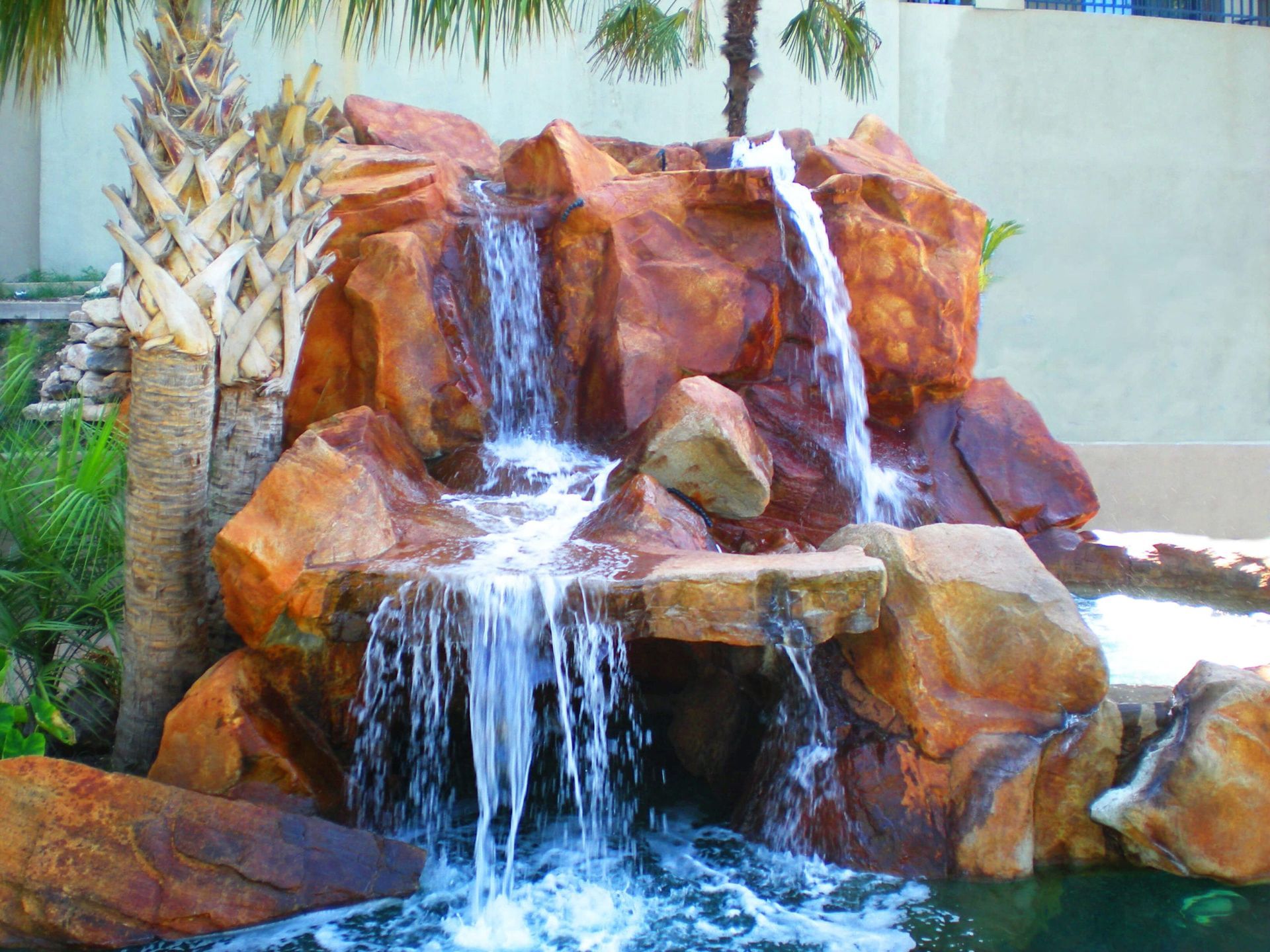 A waterfall is surrounded by rocks and palm trees