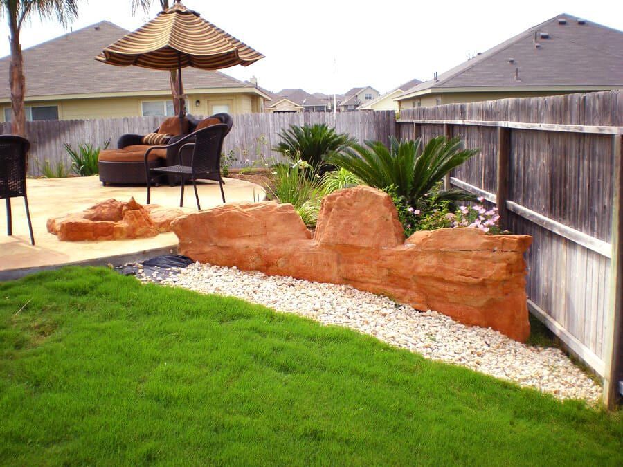 A backyard with a wooden fence and rocks