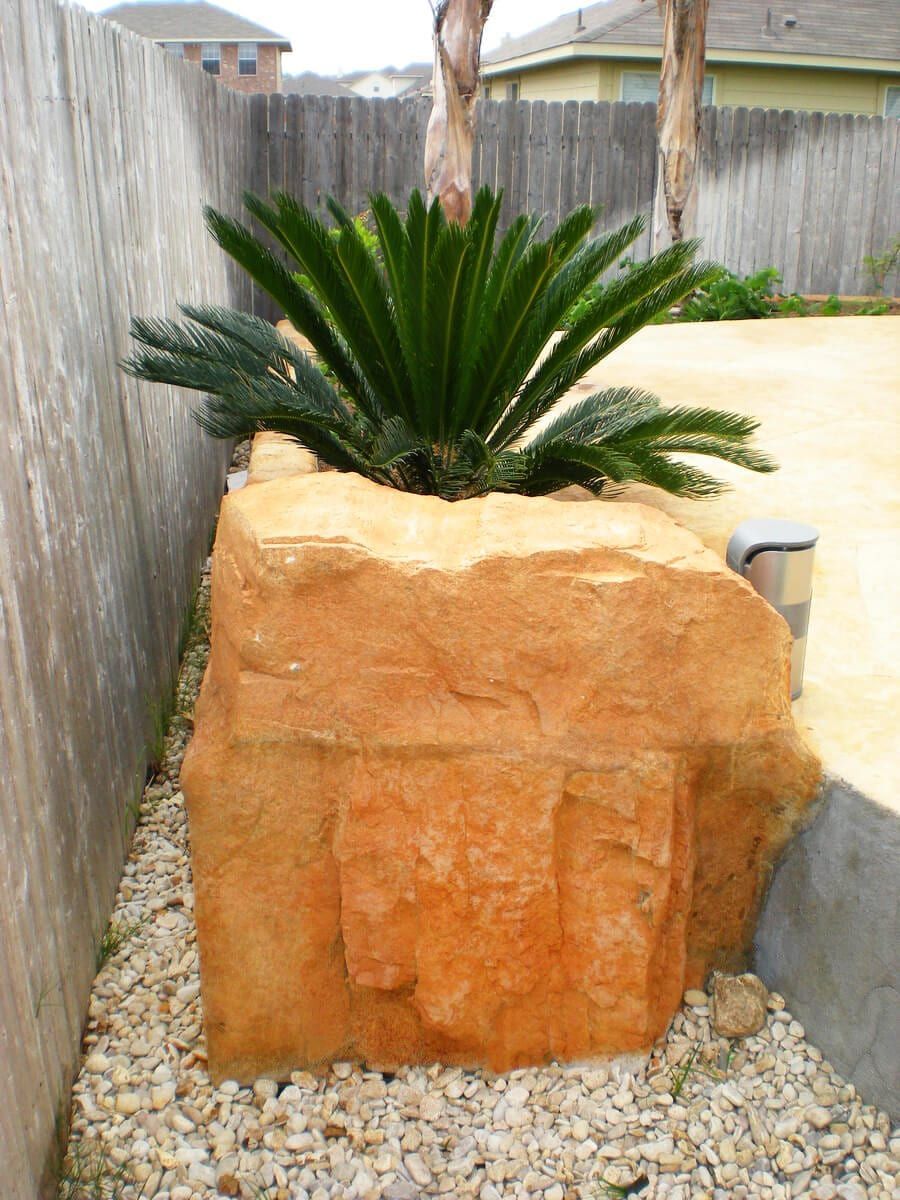 A large rock planter with a palm tree in it