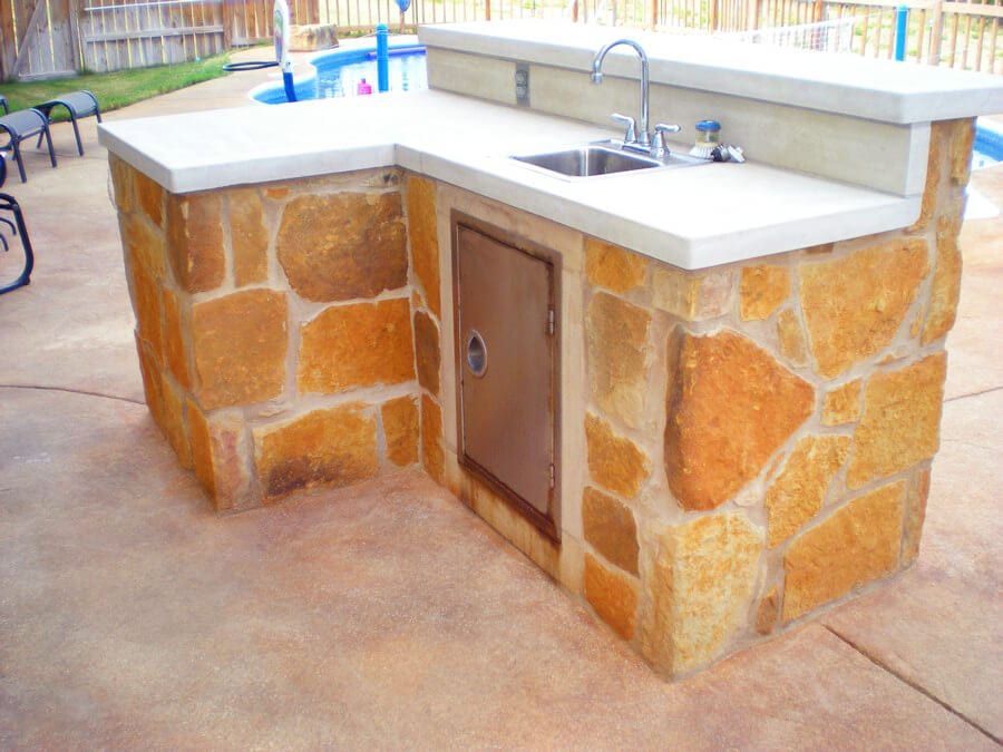 A stone kitchen with a sink and a stainless steel door