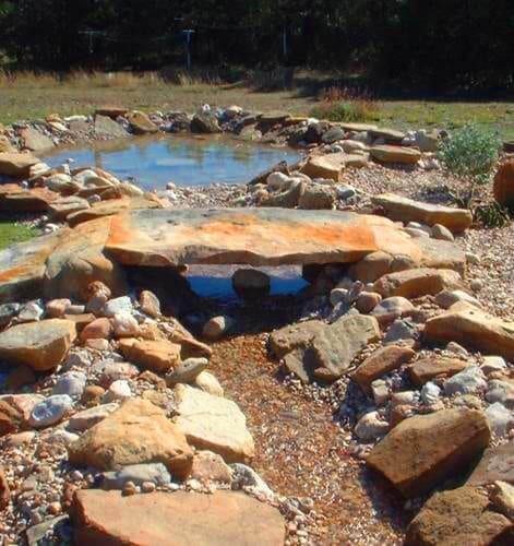 A rocky area with a small pond in the background
