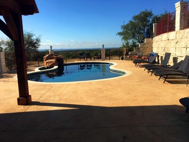 A large swimming pool surrounded by chairs and a pergola