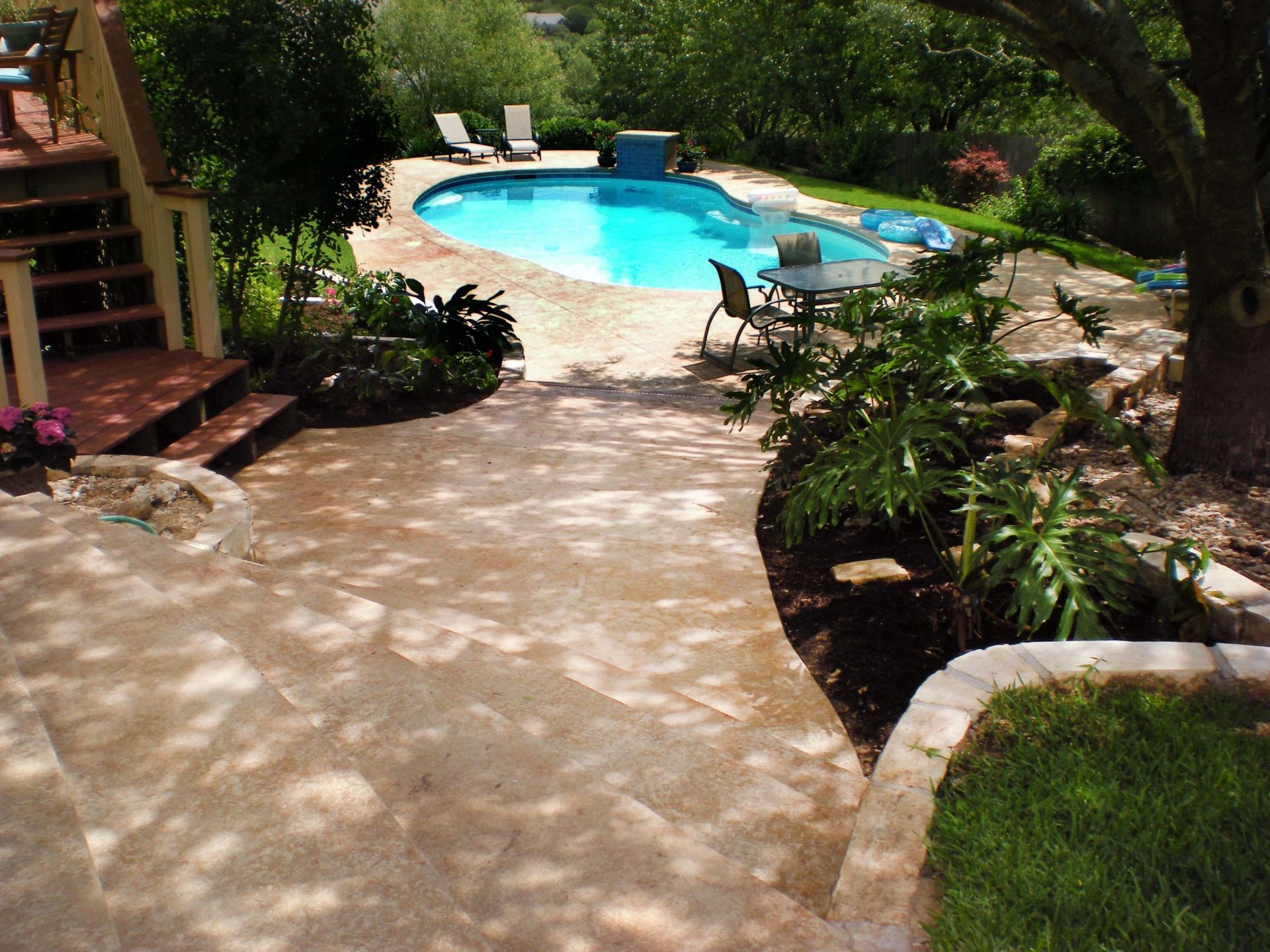 A large swimming pool is in the middle of a lush green backyard