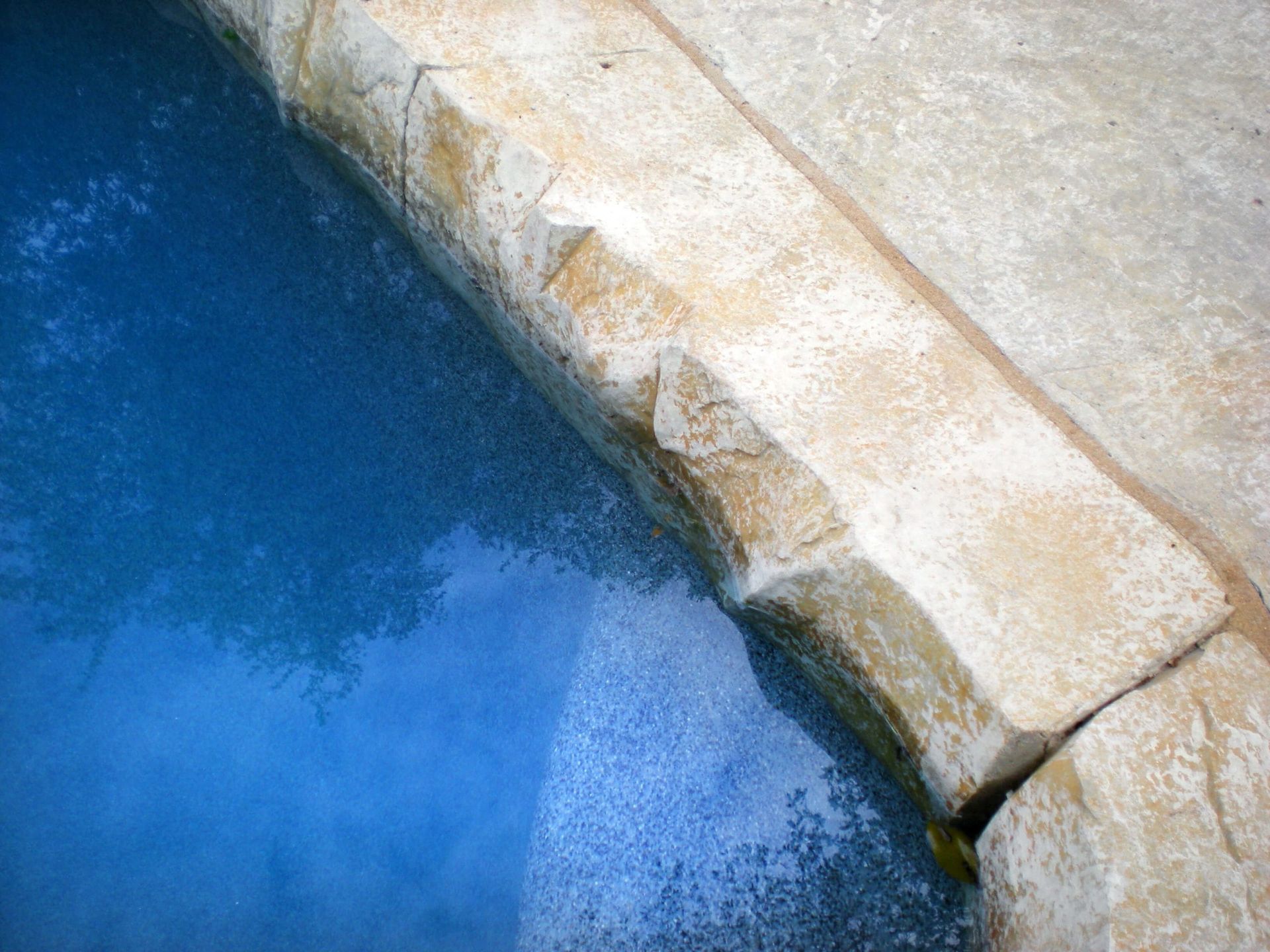 A swimming pool with a stone border and a blue water.