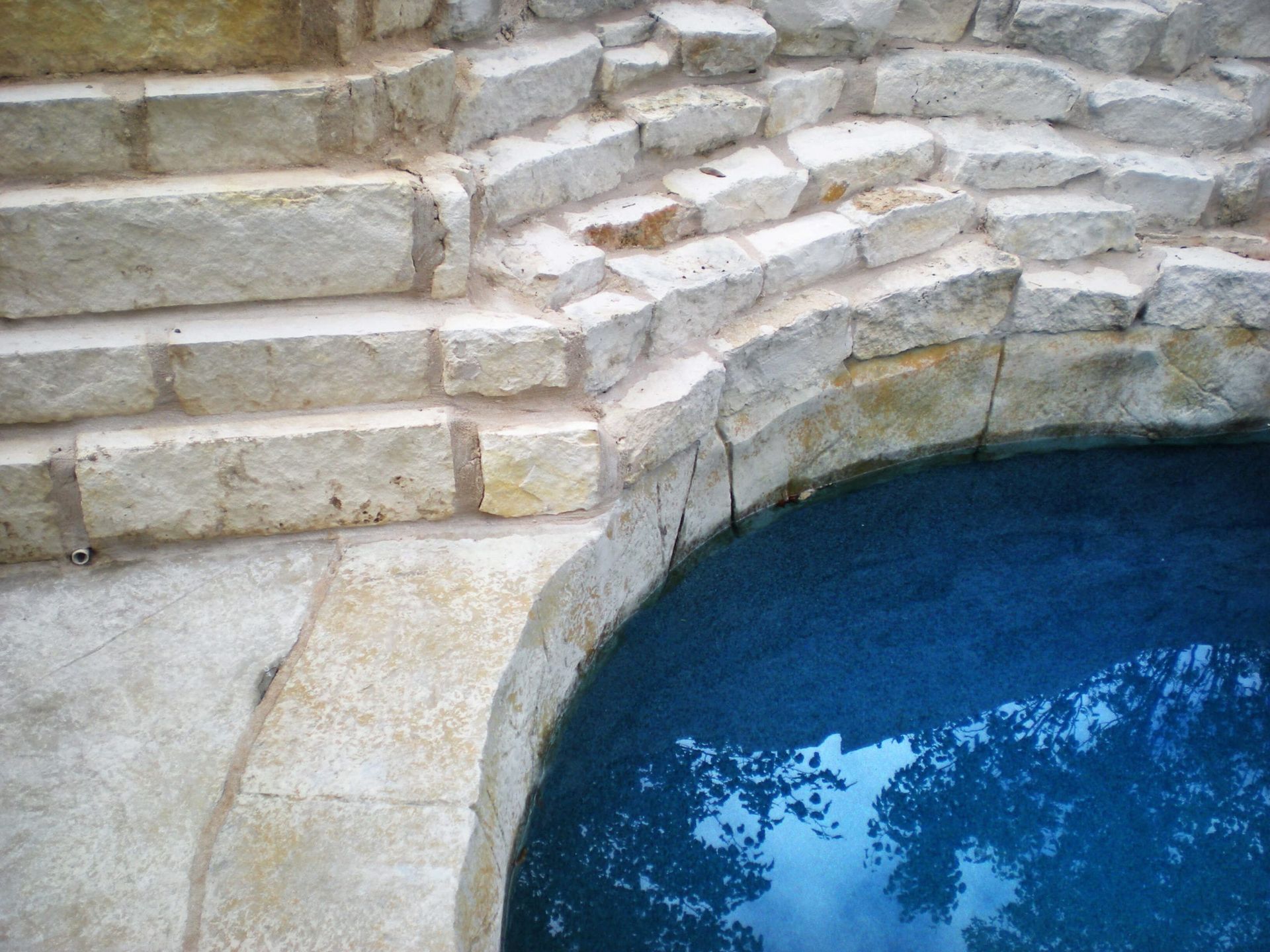 A swimming pool surrounded by stone steps and a blue water