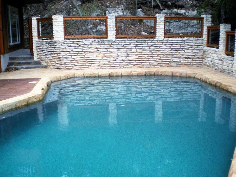 A large swimming pool with a stone wall surrounding it