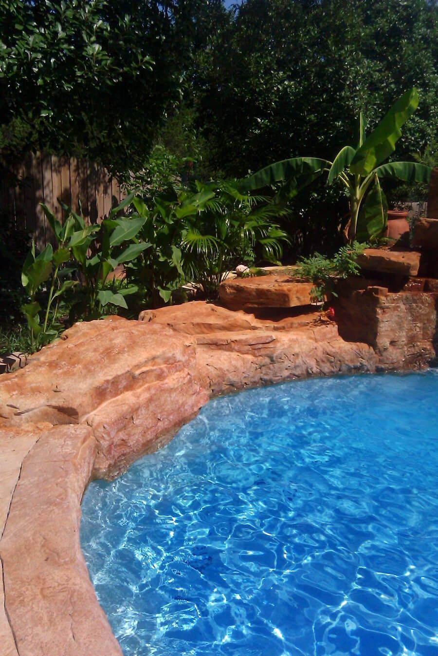 A large swimming pool surrounded by trees and rocks