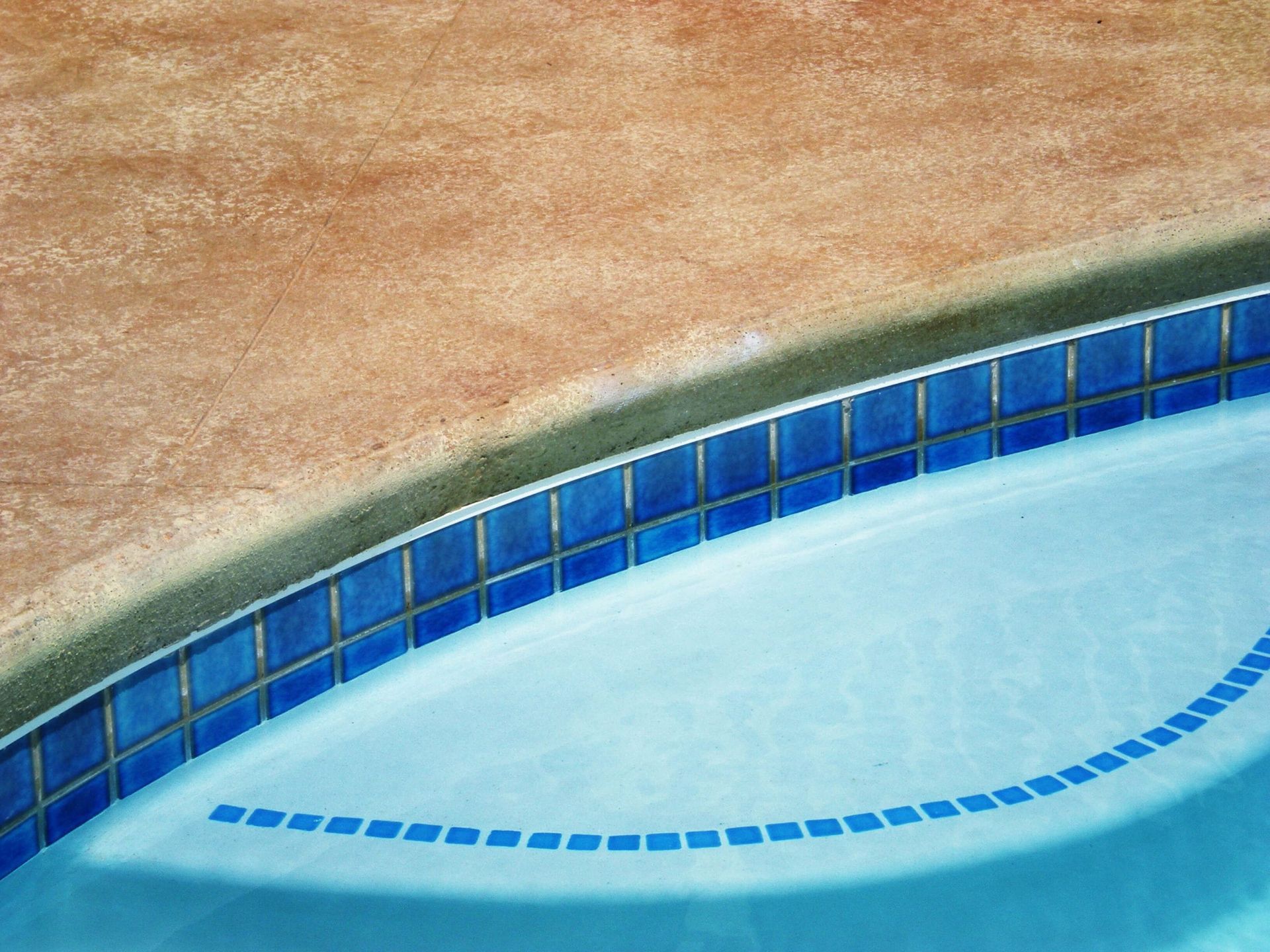 A swimming pool with blue tiles and a brown border