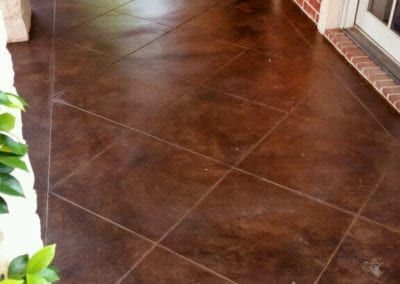 A brown tile floor with a brick wall in the background
