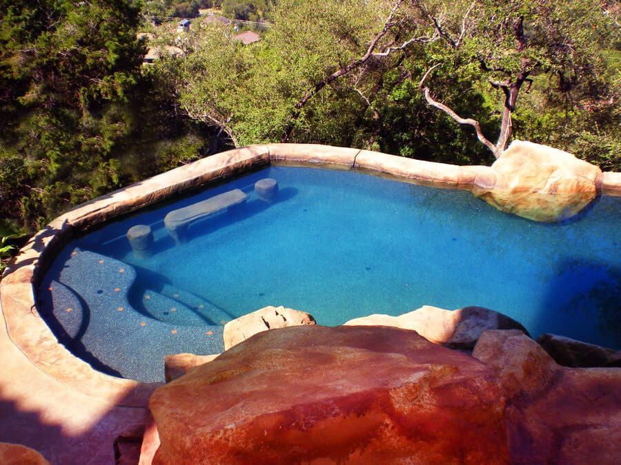 A large swimming pool surrounded by rocks and trees