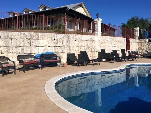 A large swimming pool with chairs and a house in the background