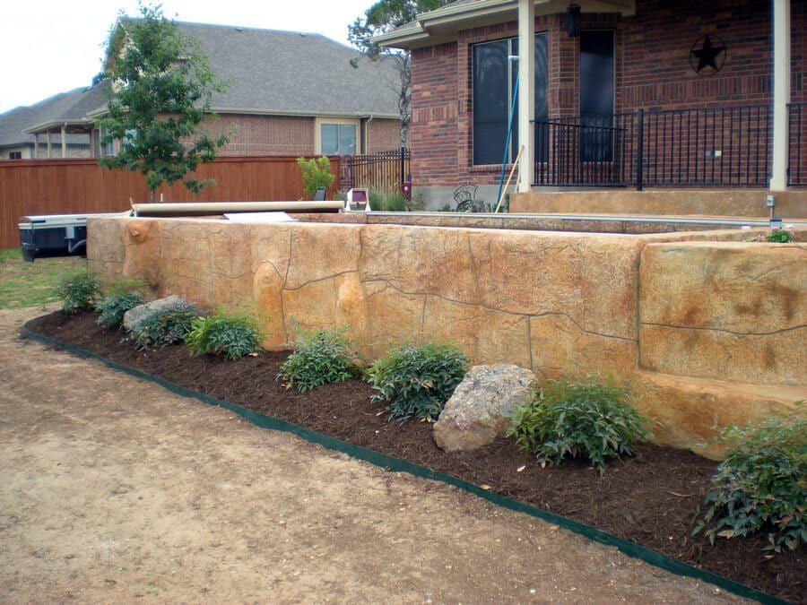 A brick house with a large stone wall in front of it