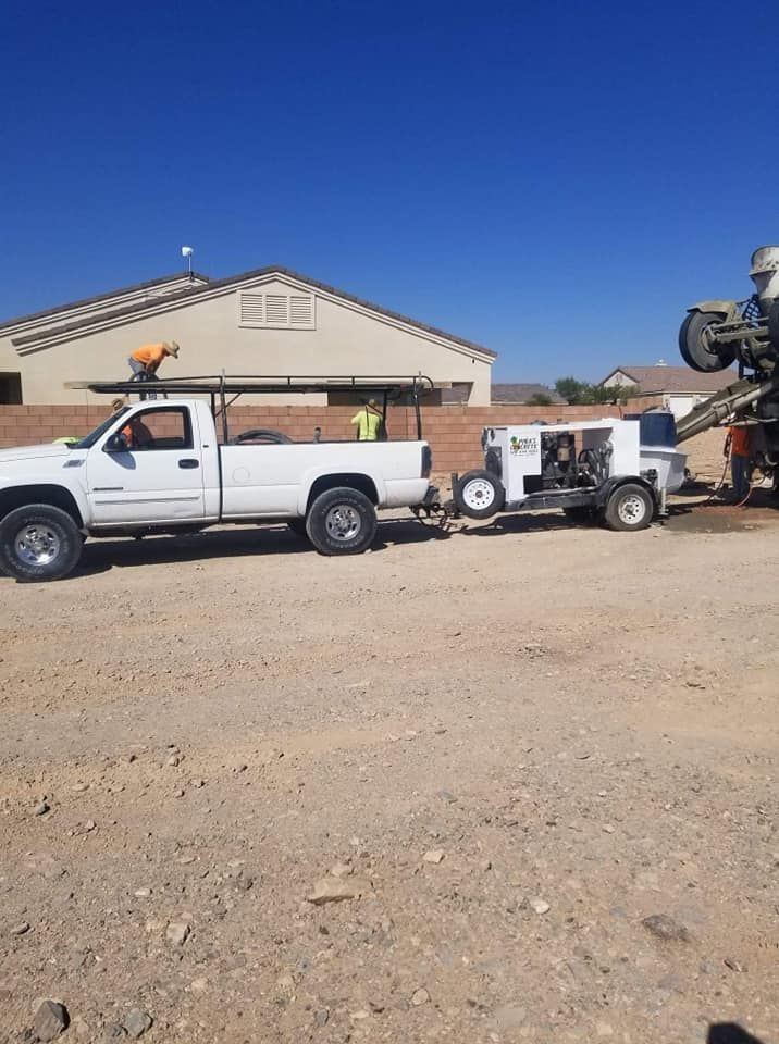 A white truck with a trailer attached to it is parked in a dirt lot.