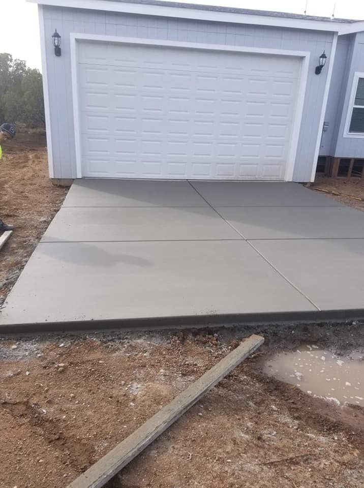 A concrete driveway is being built in front of a garage door.