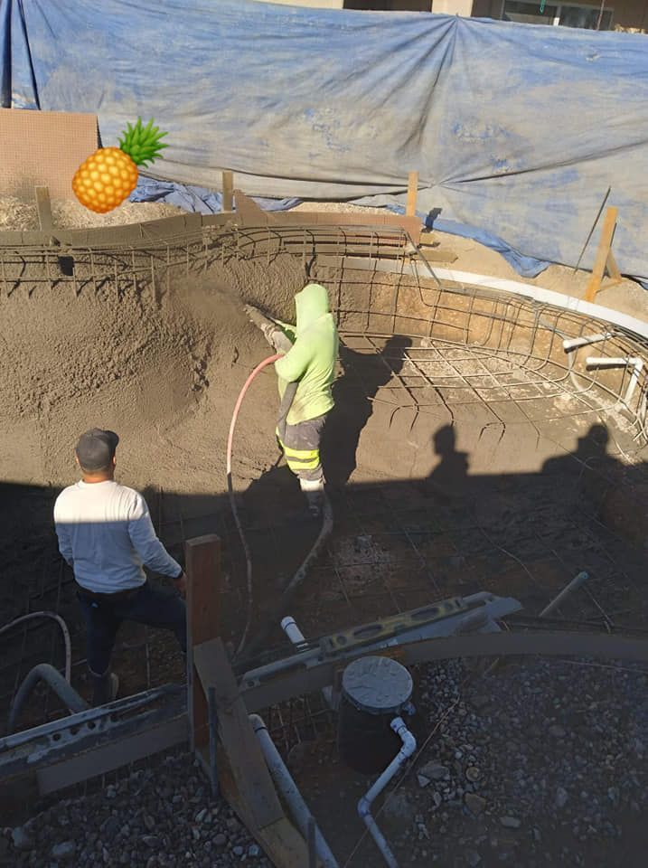 A man in a green hoodie is working on a pool.