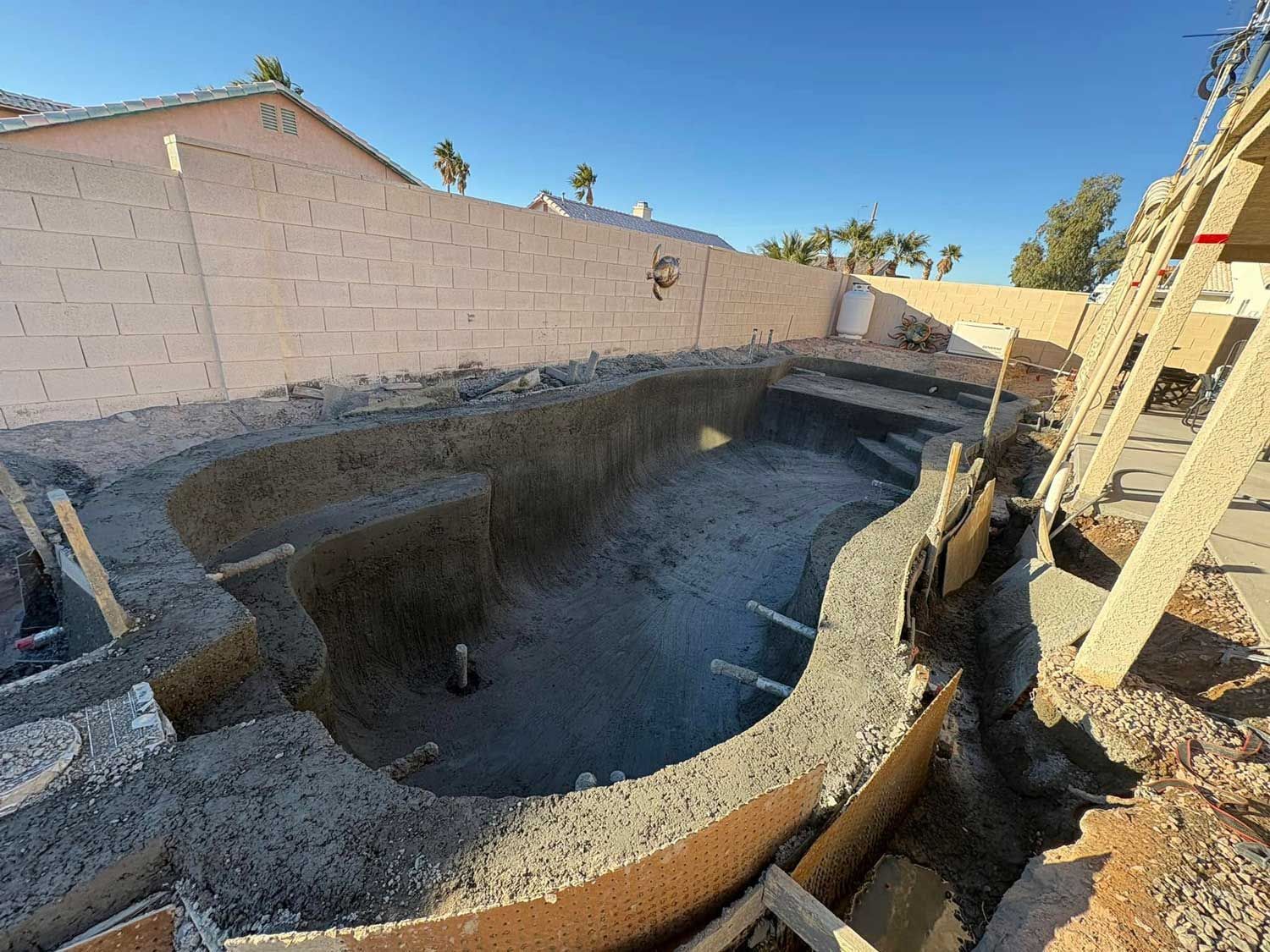 A swimming pool is being built in the backyard of a house.