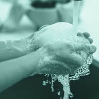 A person is washing their hands in a sink with soap and water.
