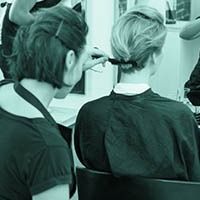 A woman is getting her hair done by a hairdresser in a salon.