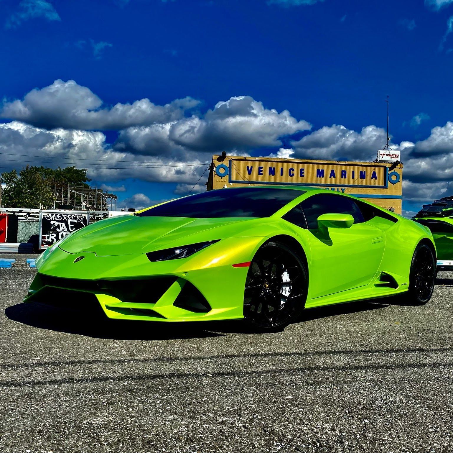 Green Lamborghini parked at Venice Marina, under a cloudy sky. | Kraft German Auto